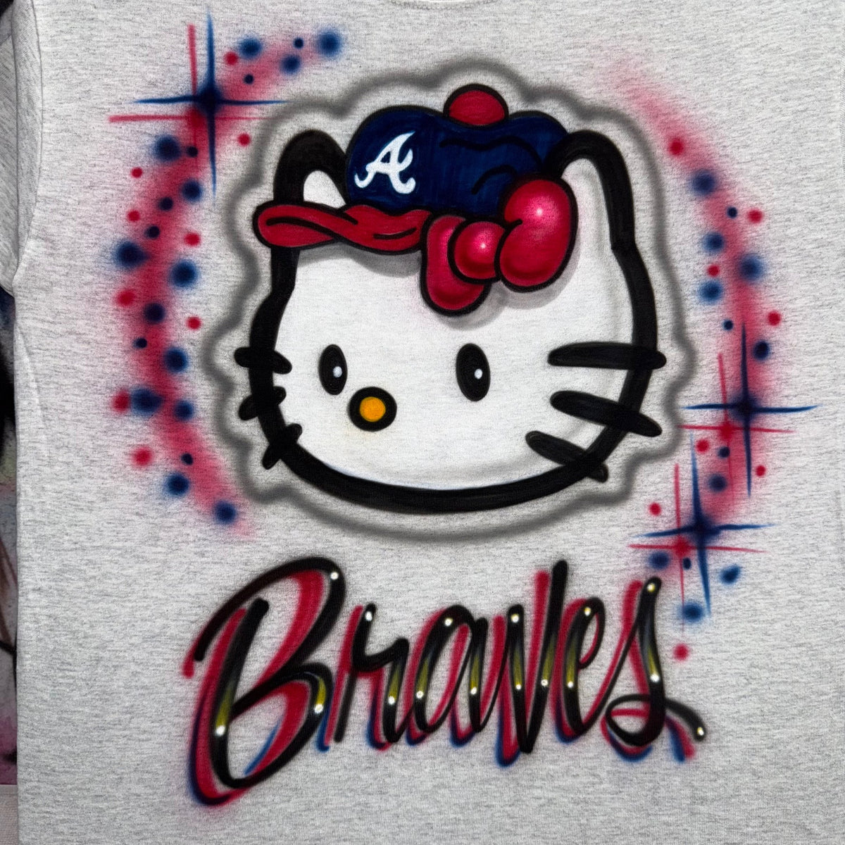 Hand-airbrushed Hello Kitty-inspired baseball shirt with Braves-inspired team colors, baseball cap, lettering and starburst accents