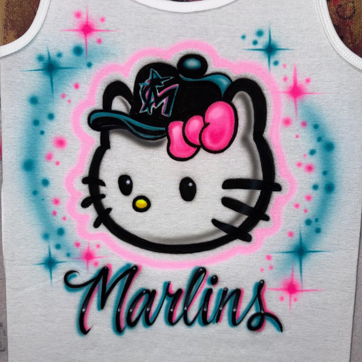 Hand-airbrushed Hello Kitty-inspired baseball shirt with Marlins-inspired team colors, baseball cap, lettering and starburst accents
