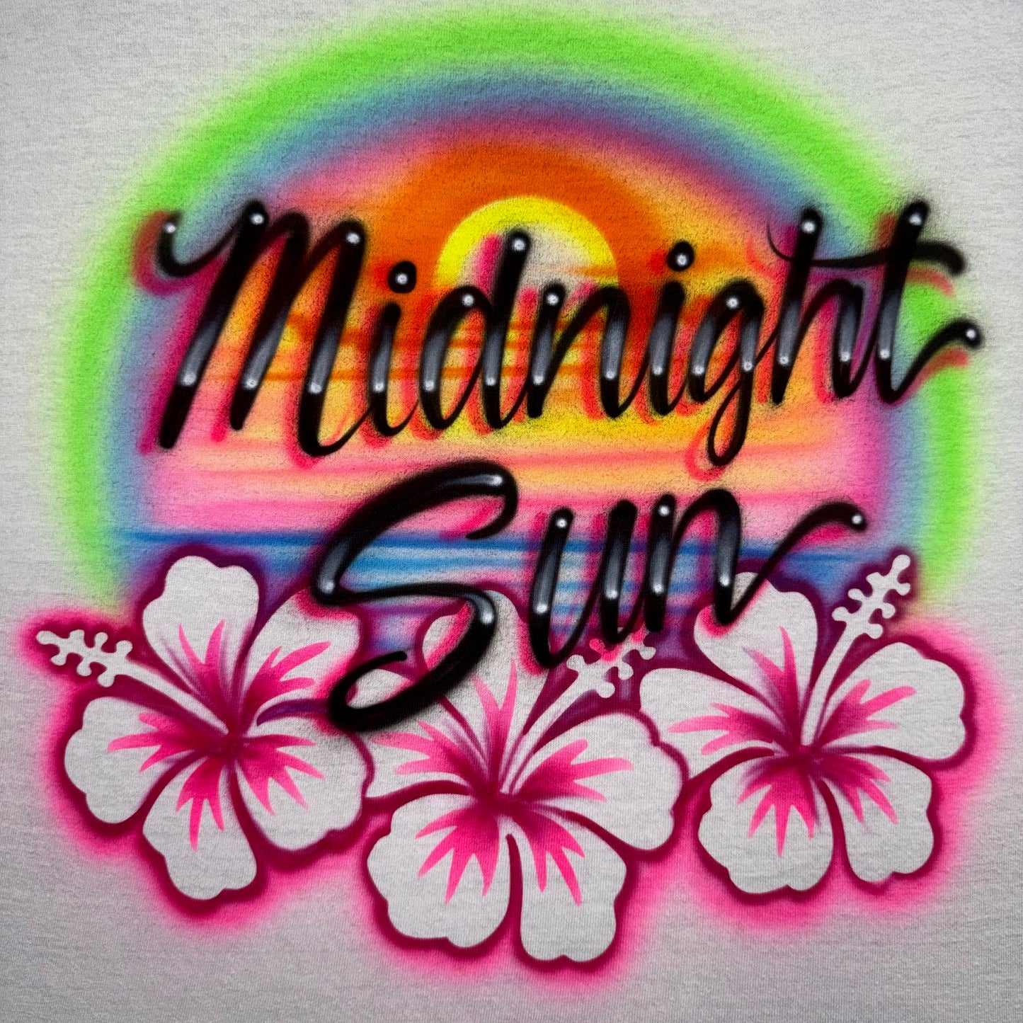 Airbrushed Midnight Sun shirt with beach sunset and hibiscus flowers, fan-inspired handmade design evoking endless summer