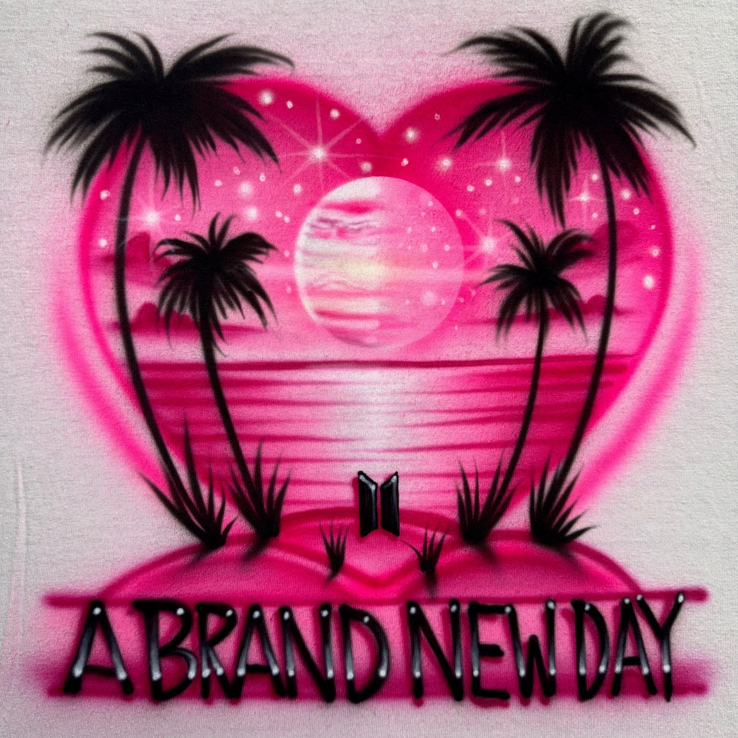 Hand-airbrushed A Brand New Day shirt with heart-shaped sunset, glowing planet, palm trees, ocean horizon, BTS logo in the sand, and star accents by Fresh Air Shirts